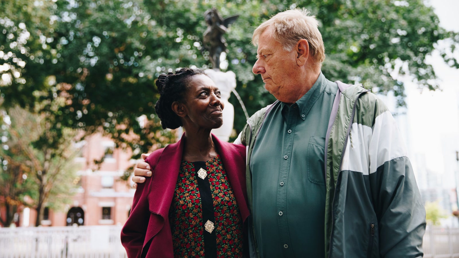 Older couple standing together in a leafy park during a walk
