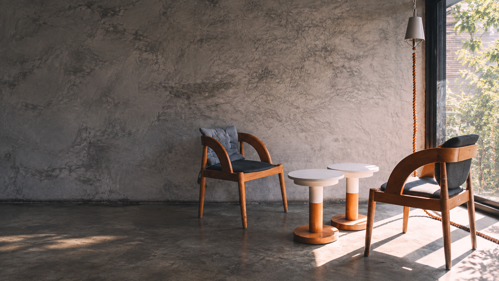 Two empty wooden chairs beside small tables in a quiet room lit by warm sunlight